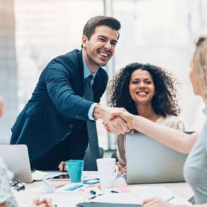 two people shaking hands across desk